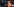 Angela Merkel lehnt an einem Stuhl, im Hintergrund Fotografen
