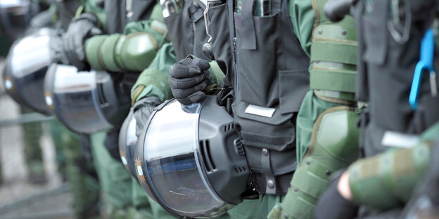 Polizisten in Kampfmontur halten ihre Helme fest