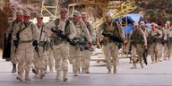 Soldaten in Tarnanzügen laufen eine Straße entlang
