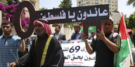 Palästinenser halten ein Schild hoch, in dem auf arabisch "wir kommen zurück Palästina" steht