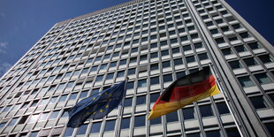 vor einem Hochhaus wehen eine Deutschland- und eine Europafahne