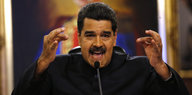 Venezuelas Präsident Maduro steht, miz beiden Händen gestikulierend, an einem Mikrofon