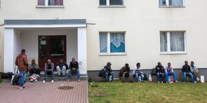 Menschen sitzen vor einem Haus