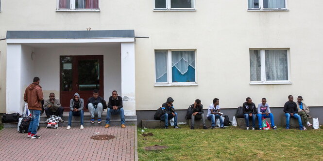 Menschen sitzen vor einem Haus