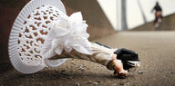 Die Figur eines Brautpaars liegt mit abgebrochenem Kopf zur Seite umgekippt auf der Straße