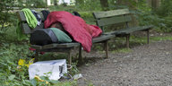 Ein Mensch schläft auf einer Parkbank
