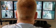 Ein Mann beobachtet Bildschirme, die Videoüberwachungsaufnahmen der Ubahn zeigen