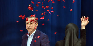 Der türkische Staatspräsident Recep Tayyip Erdogan. Im Vordergrund sind Rosenblätter zu sehen, die von einer jungen Frau mit Kopftuch in die Höhe geworfen wurden.