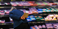 Frau steht vor vollem Einkaufsregal im Supermarkt