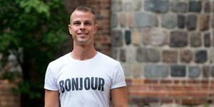 Ein Mann in weißem T-Shirt mit dem Aufdruck „Bonjour“