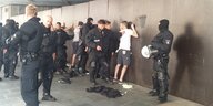 Polizsiten drücken junge Männer an die Wand und kontrollieren sie