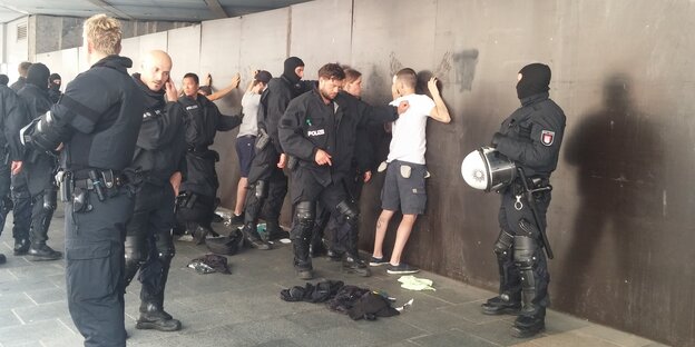 Polizsiten drücken junge Männer an die Wand und kontrollieren sie Polizsiten drücken junge Männer an die Wand und kontrollieren sie