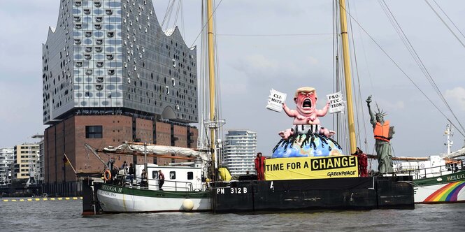 Ein Boot mit einem großen schreinden Baby vor der Hamburger Elbphilharmonie