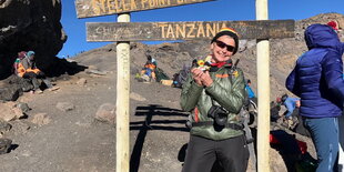 eine Frau mit Sonnenbrille auf einem Berggipfel