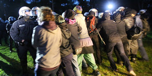 Abends: Demonstrantenkette hält gegen anstürmende Polizisten in Kampfmontur