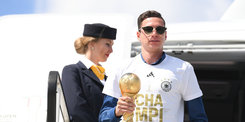 Julian Draxler mit dem Siegerpokal, im Hintergrund eine Flugbegleiterin