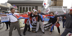 Mehrere Menschen mit Nord- und südkoreanischen Flaggen