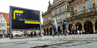 Plakatwand auf dem Bremer Marktplatz, darauf eine abstrakte Darstellung von US-Präsident Domald Trump