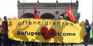 Demonstranten halten ein Plakat mit der Aufschrift "Offene Grenzen-Refugees welcome" hoch