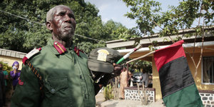 Ein Mann mit Uniform und der Biafra-Fahne in der Hand