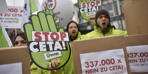 Protestierende junge Menschen neben grüner Papphand mit "Stopp Ceta"-Aufschrift