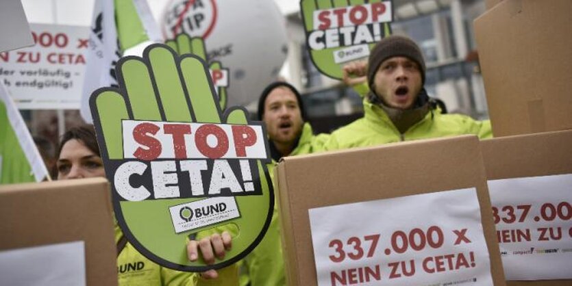 Protestierende junge Menschen neben grüner Papphand mit "Stopp Ceta"-Aufschrift