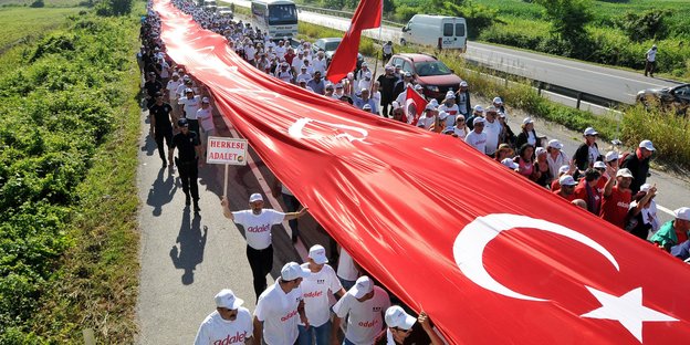 Eine Menschenmenge trägt eine riesige Türkei-Fahne über ihren Köpfen