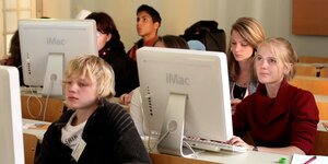 Schüler und Schülerinnen sitzen vor einem Computer