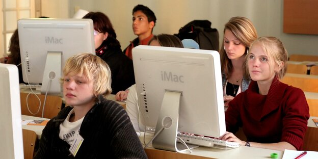 Schüler und Schülerinnen sitzen vor einem Computer