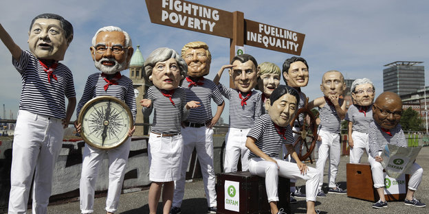 Menschen tragen Masken der Staatsoberhäupter der G20-Teilnehmer