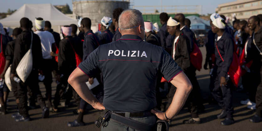 Ein Polizist steht vor einer Menschenmenge