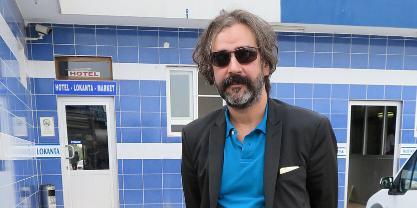 Deniz Yücel mit Sonnenbrille vor einem blauen Haus