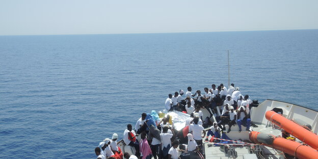 Viele Menschen auf einem Boot, dahinter der Horizont