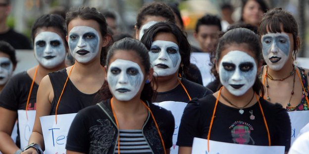 Frauen mit weiß bemalten Gesichtern demonstrieren
