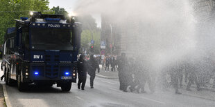 Ein blauer Wasserwerfer spritzt Wasser auf der Straße