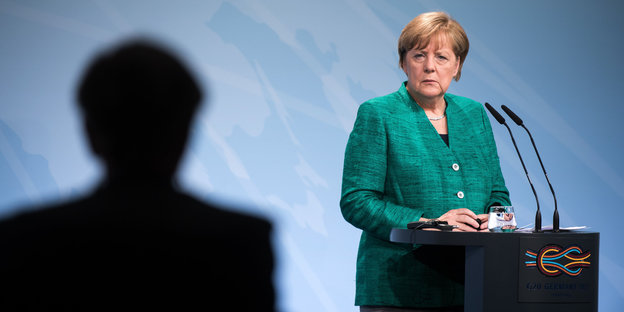 Bundeskanzlerin Angela Merkel am Rednerpult mit einem großen Schatten neben ihr