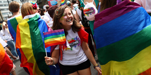 Menschen stehen mit Regenbogenfahnen auf der Straße