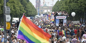 Eine Straße voller Menschen, zudem eine Regenbogen-Fahne