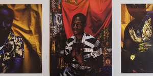Drei Fotografien von Männern hängen nebeneinander an einer Wand