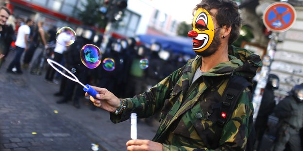 ein Mann mit Clownsmaske macht Seifenblasen auf der Straße