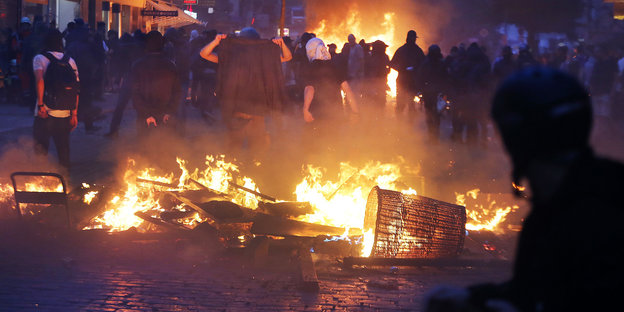 Demonstranten stehen vor brennenden Barrikaden
