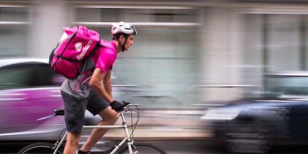 ein Radfahrer mit einer pinkfarbenen Transportrucksack für Essen auf dem Rücken