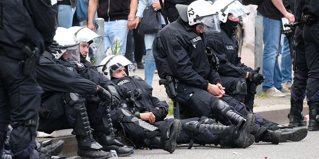 Polizisten sitzen erschöpft am Straßenrand