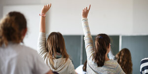 Zwei Schülerinnen strecken ihre Hände nach oben.