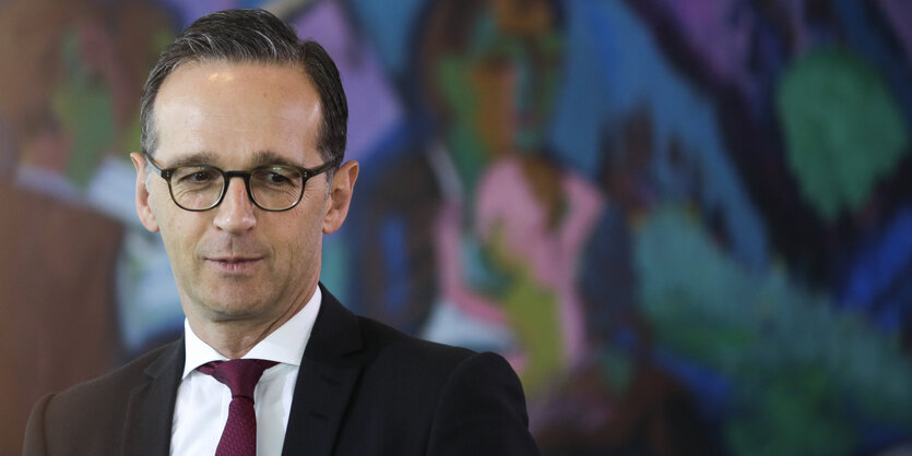 Justizminister Heiko Maas steht vor einer bemalten Wand