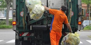 Ein Mann wirft Müll in den Müllwagen