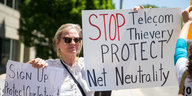 Eine Frau hält ein Schild hoch mit der Aufschrift "Stop Telekom Thievery, Protect Net Neutrality"