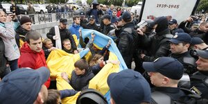Menschen mit der ukrainischen Flagge in einer Menge aus Polizisten