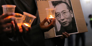 Zwei Männer halten Kerzen und ein Bild von Liu Xiaobo
