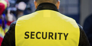 Auf der Weste eines Mannes steht "Security".